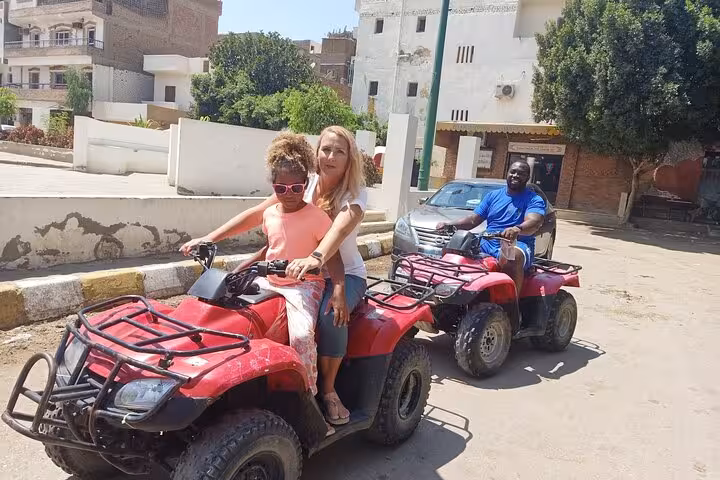 Family riding red ATVs on a private Giza Pyramids and Sphinx tour, combining quad bike and camel ride