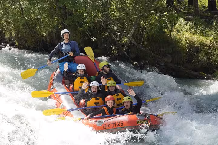 Family enjoying an exhilarating rafting adventure on a rapid river in Engadin, surrounded by lush greenery and excitement.
