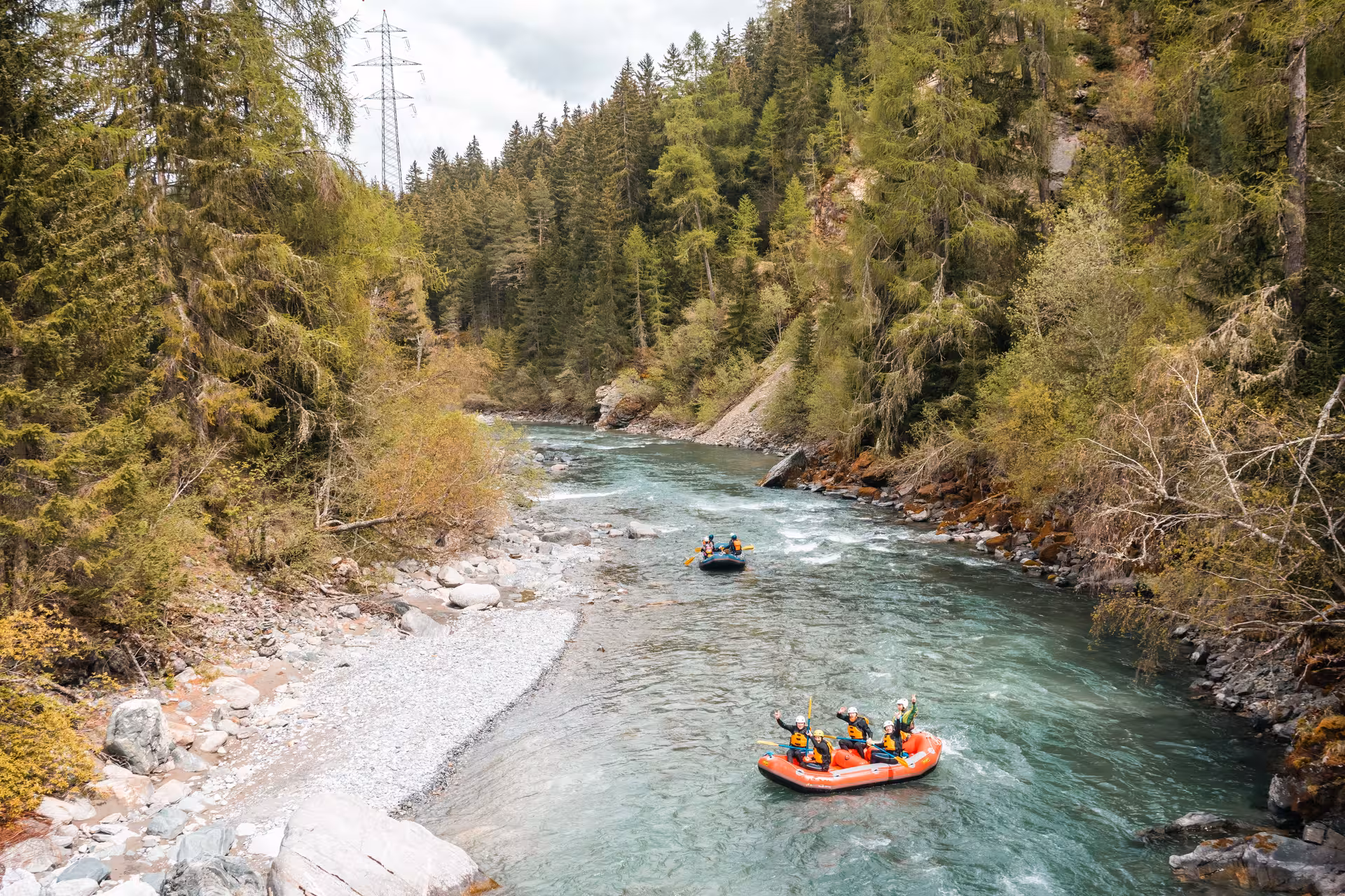 Two rafts navigate serene Engadin river surrounded by lush forest, perfect for family fun.