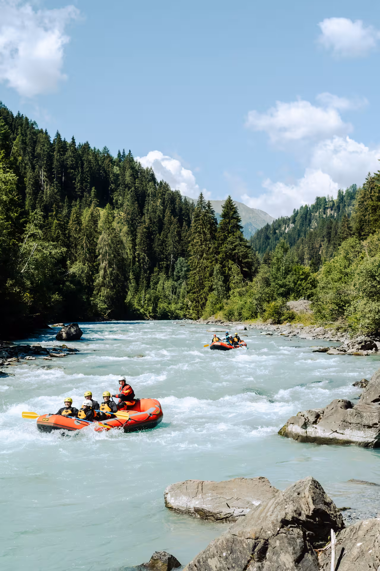 Families experience exciting rafting under blue skies and scenic forests in Engadin.