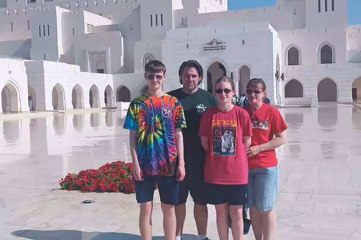 Family posing at Royal Opera House Muscat on a guided city tour exploring Oman cultural highlights
