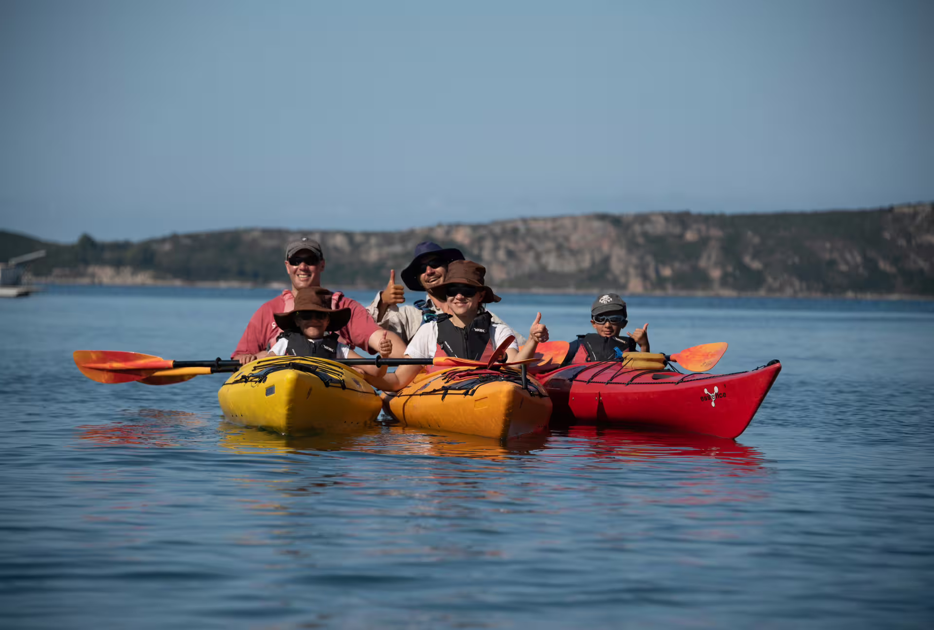 Family group in colorful kayaks on calm Navarino Bay, Pylos, Greece, enjoying a guided sea kayaking tour