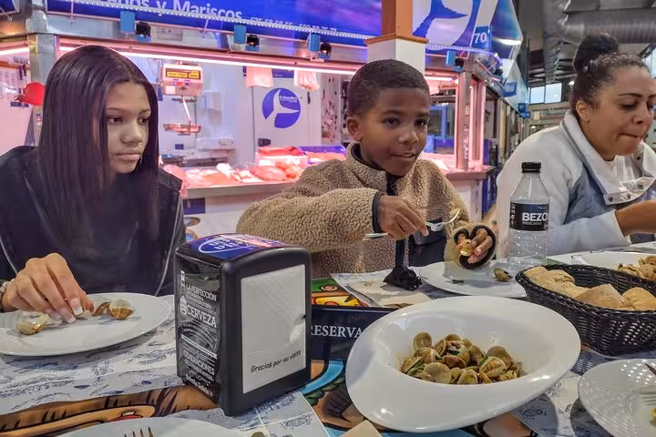Family enjoying traditional seafood dishes at a bustling market during the Taste of Marbella Food & Market Tour.