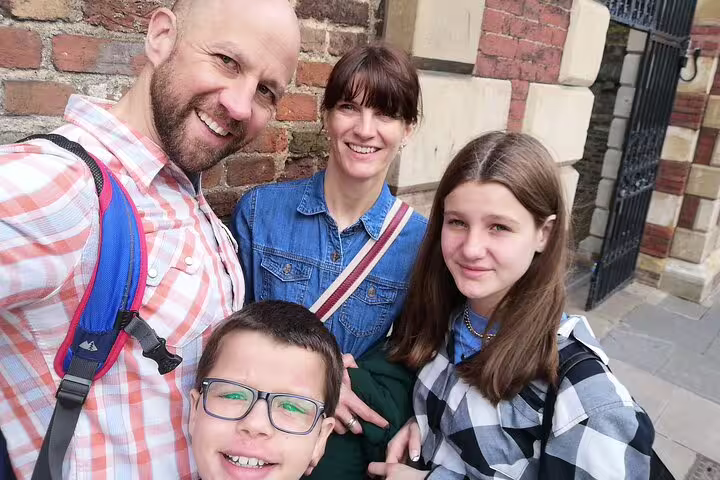 Family of four smiling together outside a historic Cambridge brick building during a self-guided tour