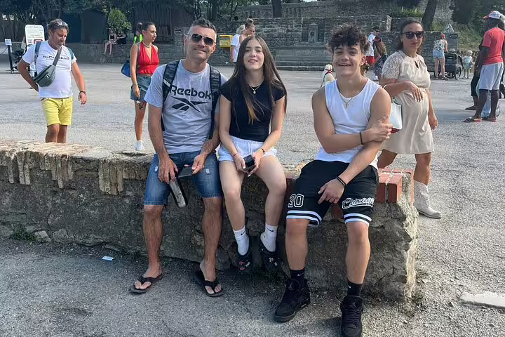 Family of three resting on stone wall during self-guided walking tour in Carcassonne medieval city