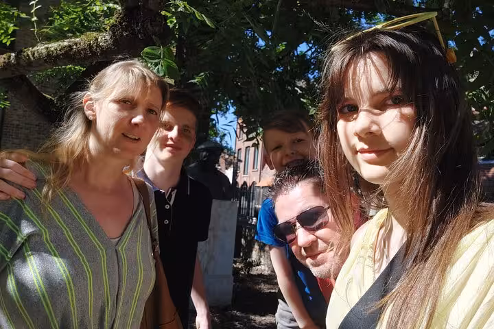 Family of five posing together under a tree during a walking tour in Bruges