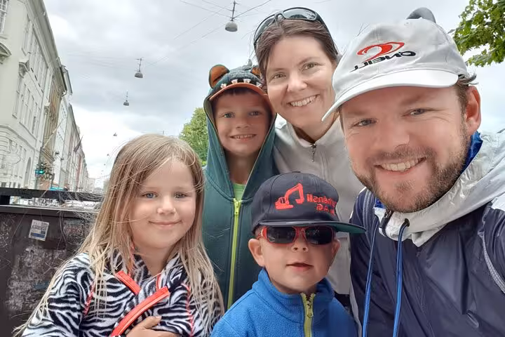 Family of five smiling together on a self-guided walking tour in Copenhagen on a cloudy day