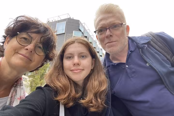 Family of three taking a selfie outdoors in Barcelona with modern building in background