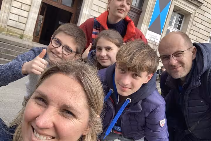 Family group selfie smiling in front of historic Bordeaux Old Town building during walking tour