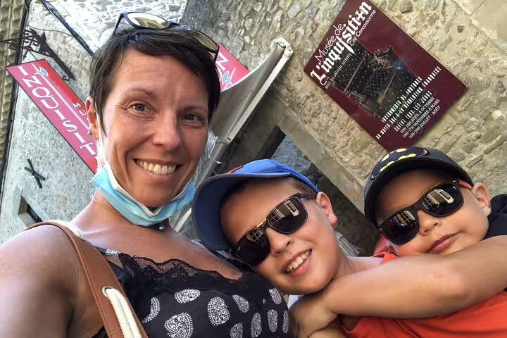 Woman with two children smiling outside Musée de l'Inquisition in Carcassonne medieval city