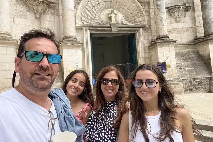 Family of four smiling in front of a historic stone church in La Rochelle Old Town