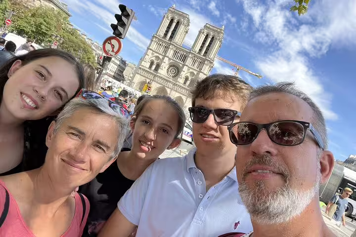 Family selfie in front of Notre-Dame Cathedral in Paris on a sunny day