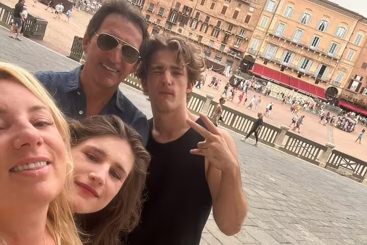 Family of four taking a selfie at Piazza del Campo in medieval Siena, Italy