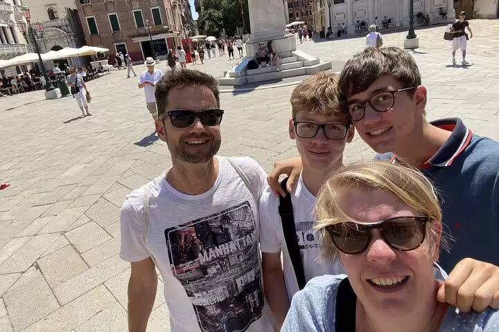 Family of four taking a selfie in a sunny Venice piazza during a self-guided walking tour
