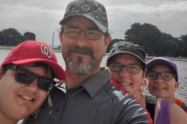 Family of four smiling near the Reflecting Pool with Washington Monument in background, Washington DC