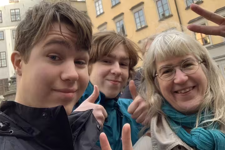 Family of three smiling on Stockholm ghost tour selfie in old town street
