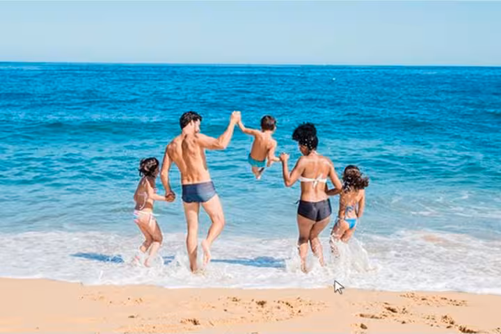 Family playing in Atlantic surf on Algarve beach, stop on private boat tour from Faro with swim time