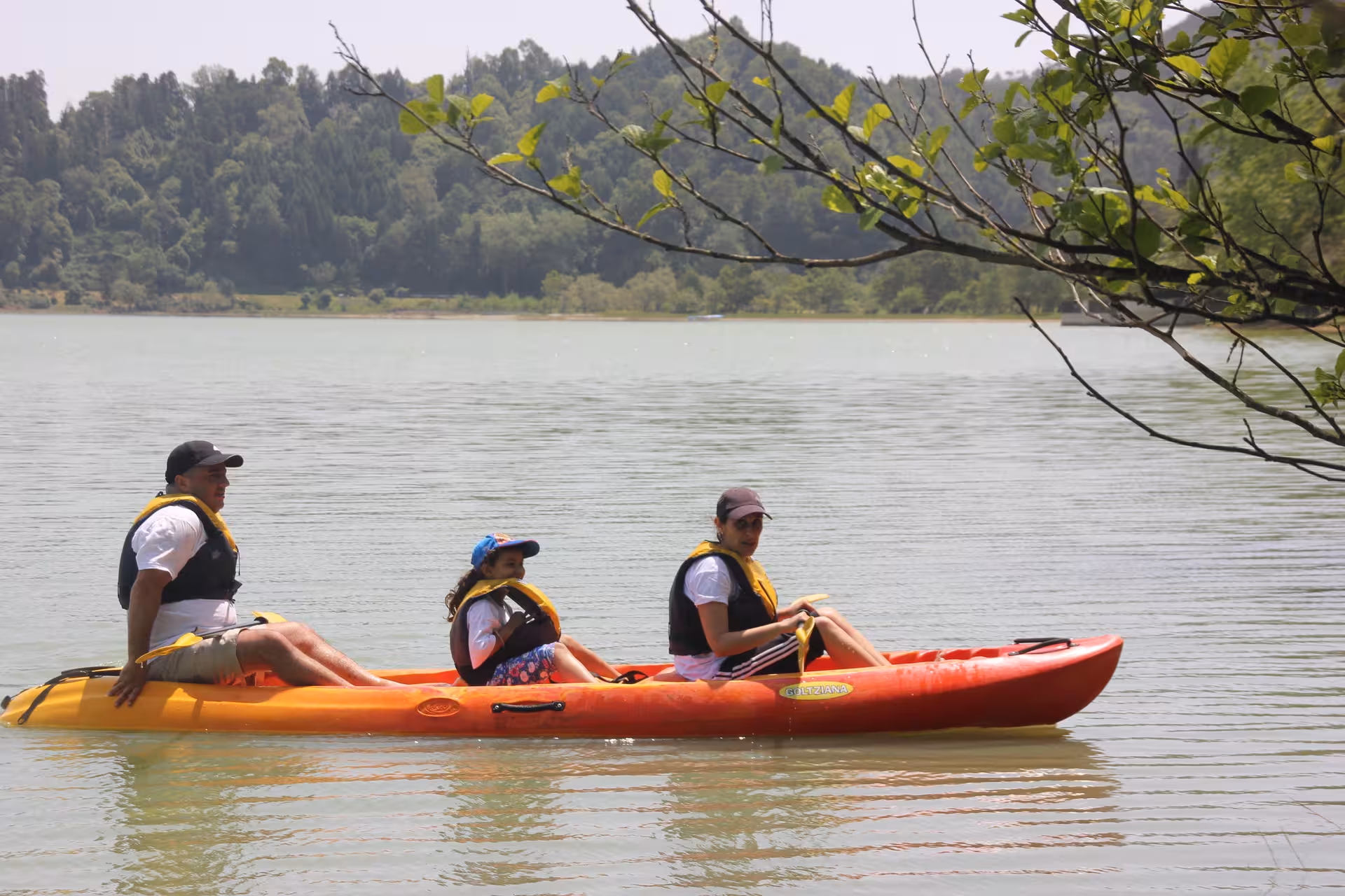 Family paddles a tandem canoe on a calm lake, half-day canoeing tour with transportation and life jackets