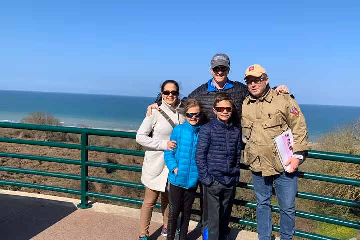 Family group posing at D-Day Beaches overlook with ocean views on guided tour from Le Havre