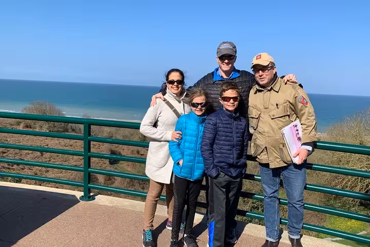 Family group posing at a scenic overlook above Normandy coastline on a sunny day
