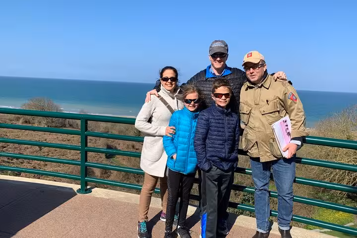 Family group posing at a scenic overlook above Normandy Beach on a D-Day tour from Cherbourg