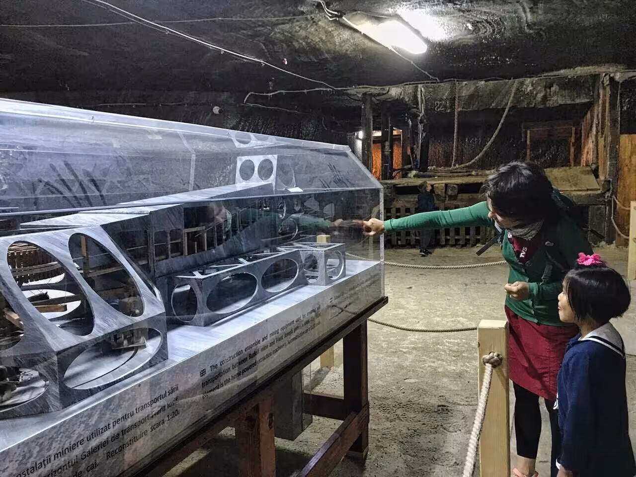 Family viewing historical mining equipment scale model exhibit deep inside Turda Salt Mine near Cluj Romania