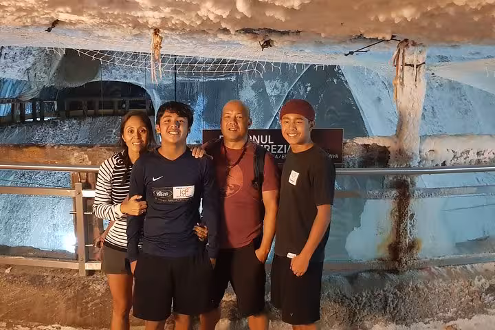 Family of four posing together inside Turda Salt Mine with salt-covered walls and cavern in background