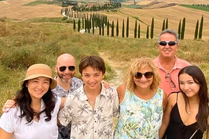 Smiling family posing along the scenic cypress-lined roads of Val D'Orcia on a picturesque Tuscan tour.