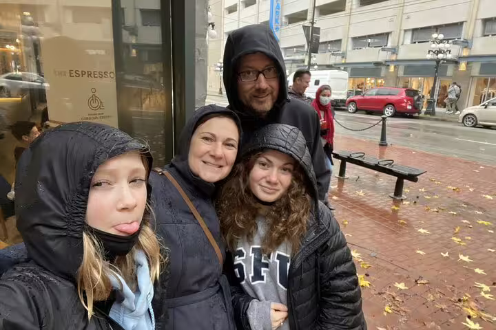 Family of four smiling together on a rainy day in Vancouver's Gastown neighborhood