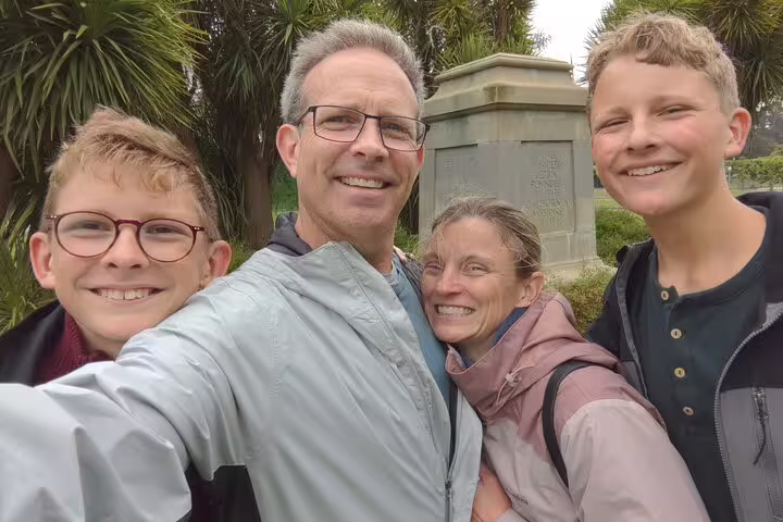Family of four smiling together on a walking tour in Golden Gate Park, San Francisco
