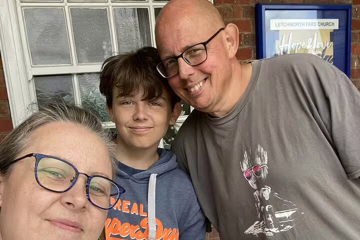Family of three smiling outside Letchworth Free Church on a walking tour of Letchworth Garden City