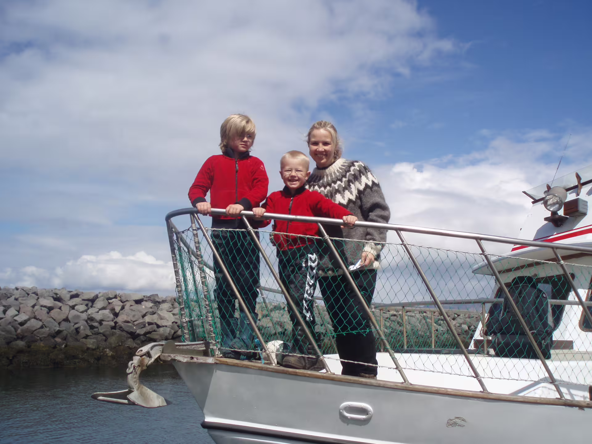 Family with two children standing on boat deck at Reykjavik harbor on whale watching tour