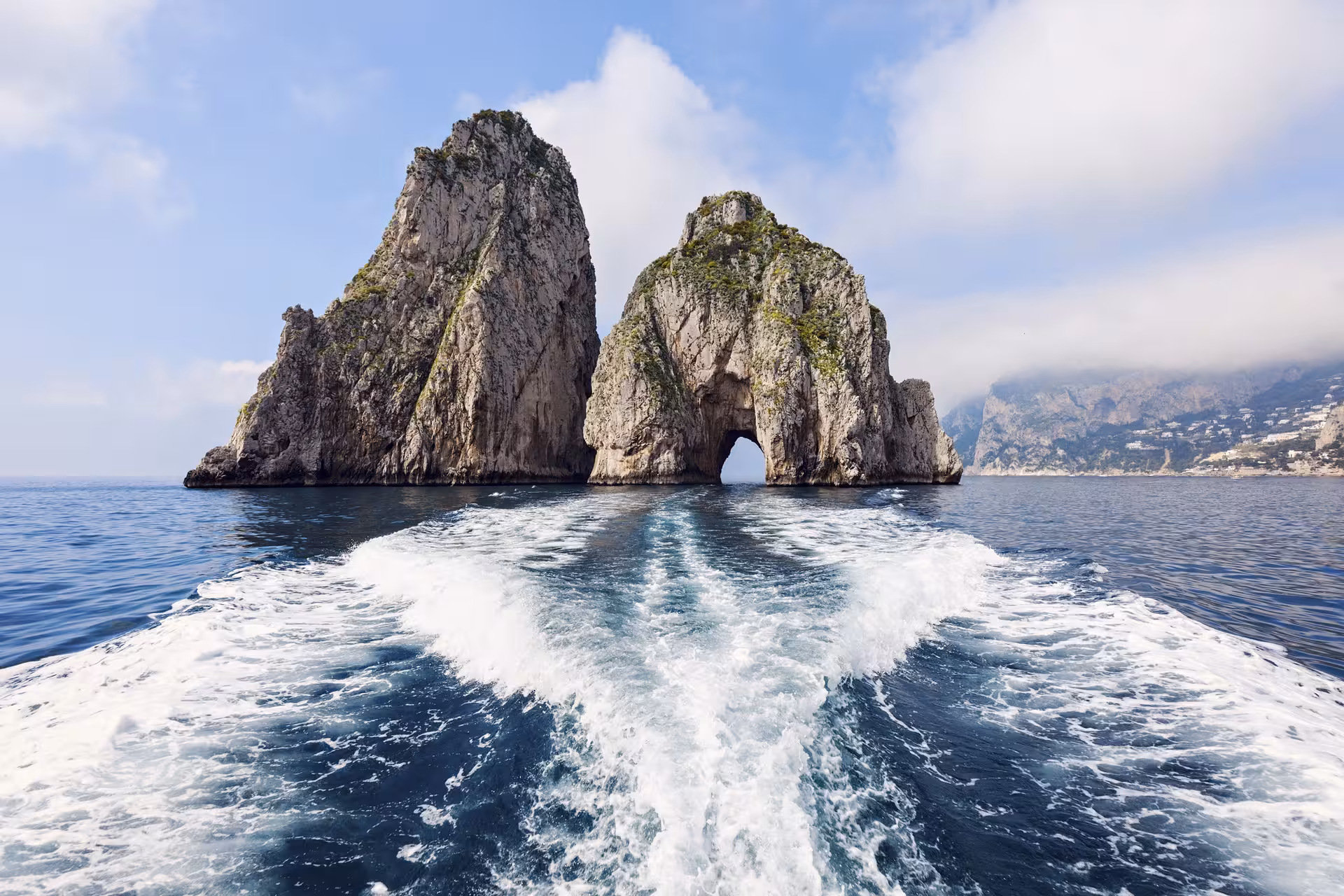 View of Faraglioni rock formations from a boat tour in Capri, showcasing the stunning Mediterranean landscape.