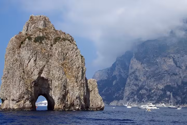 Close-up of Faraglioni rocks with yachts nearby on a sunny day during a hydrofoil tour around Capri.