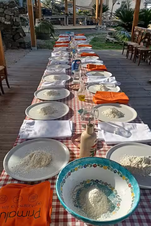 Outdoor pizza-making workshop table with flour and bowls at agriturismo, plus wine and limoncello tasting experience