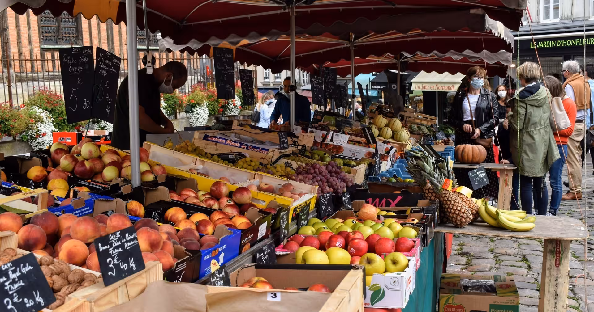 Outdoor farmers market stall with apples, grapes and tropical fruit, ideal stop on a gourmet market tour