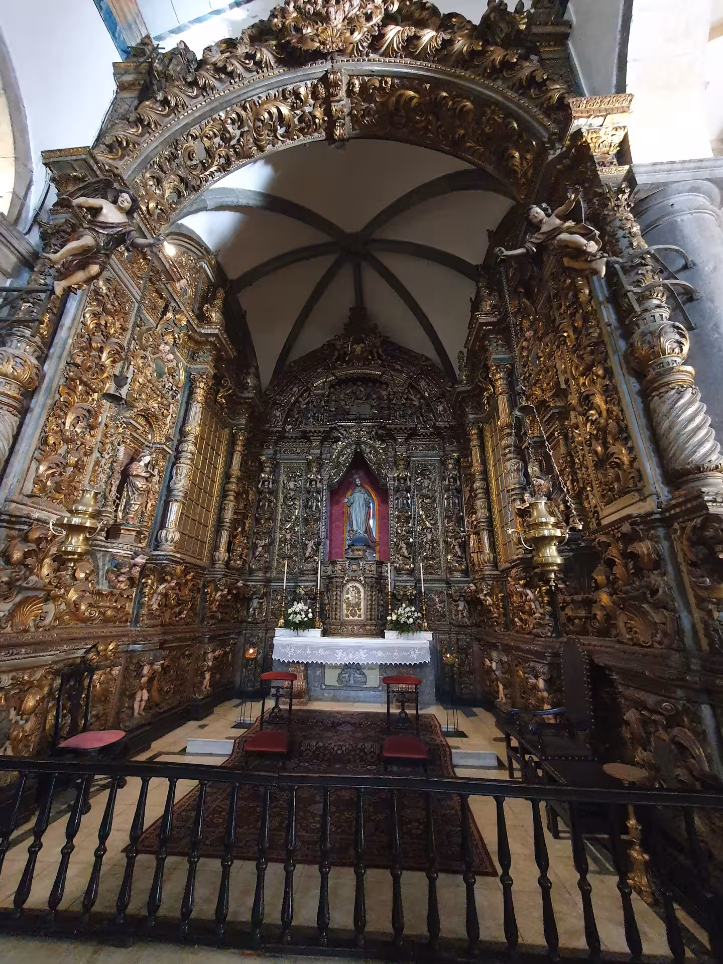 Intricately carved altar in a Faro church featuring lavish gold detailing and religious figures, ideal for architectural tours.