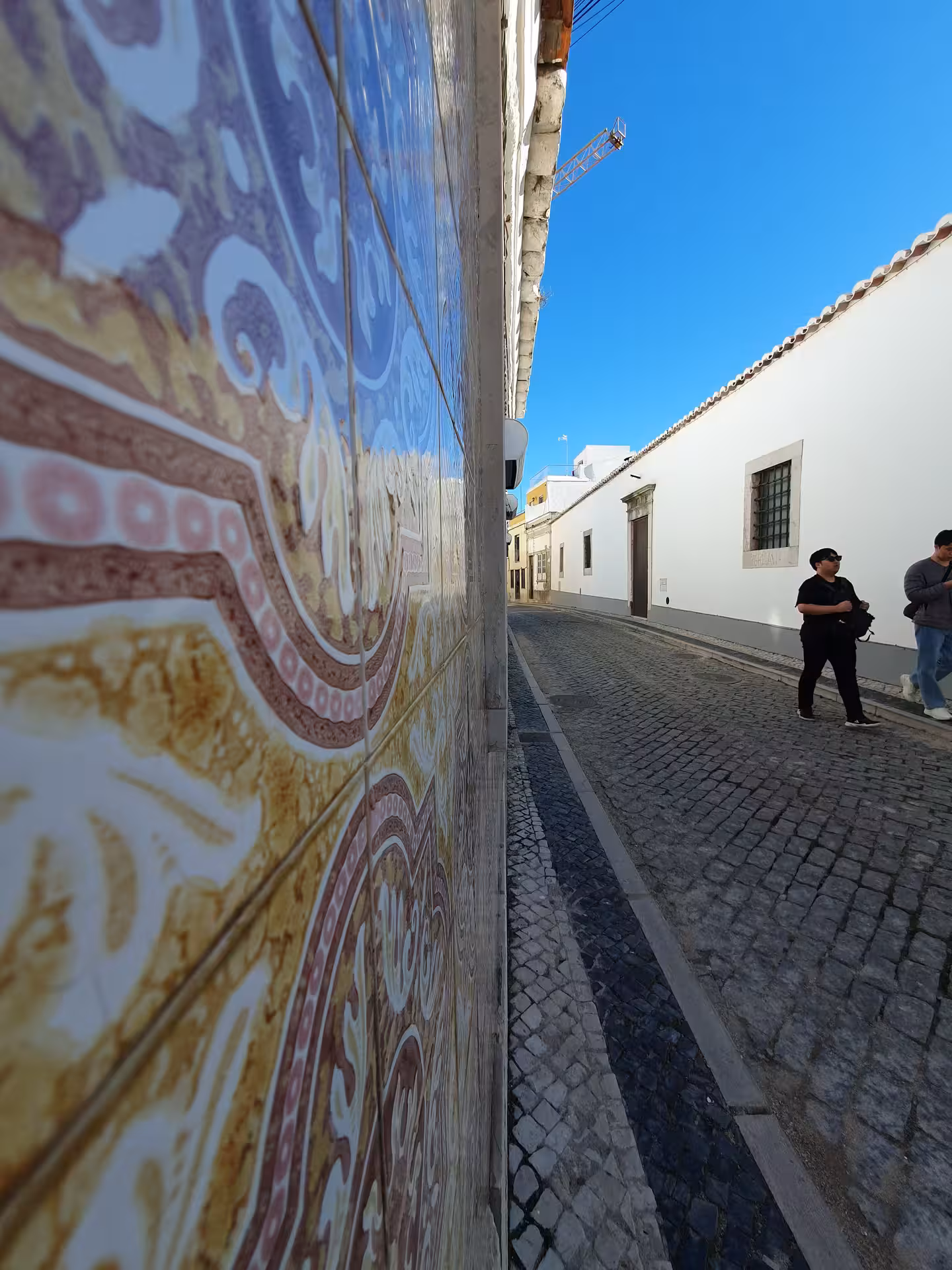 Charming cobblestone street with traditional Portuguese tiles and blue sky in Faro, ideal for a scenic walking tour.