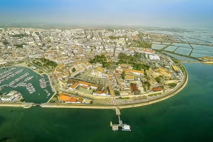 Aerial view of Faro's historic waterfront and marina in Algarve, Portugal, showcasing vibrant architecture and scenic coastline.
