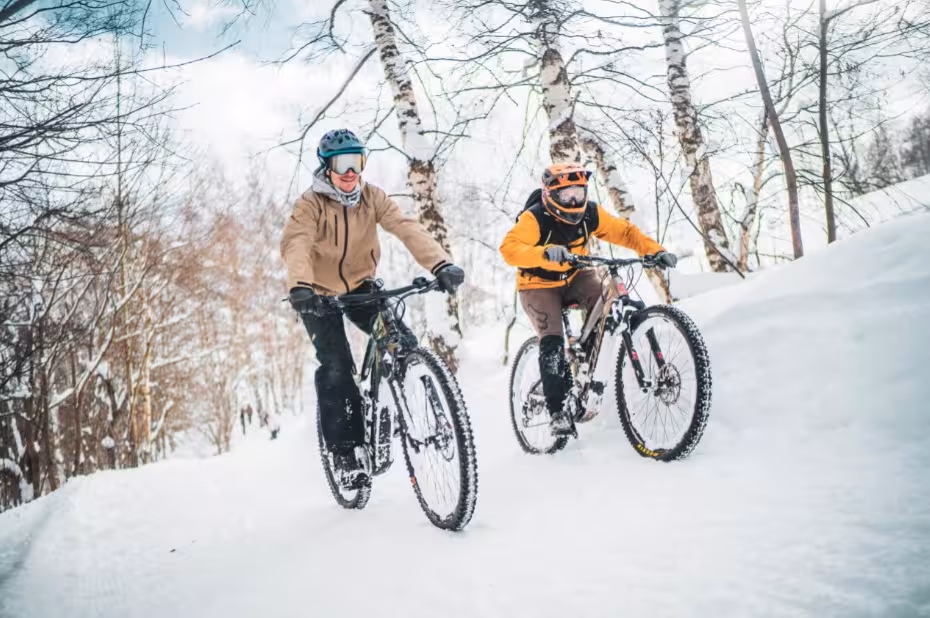 Deux cyclistes en fat bike roulent sur un sentier enneigé en forêt, expérience neige guidée et sportive