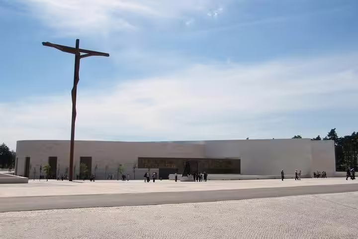 Spacious plaza and modern basilica with towering cross in Fatima, Portugal, ideal for private half-day tours from Lisbon.