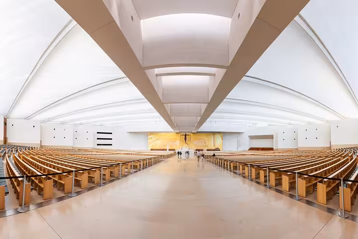 Spacious interior of a modern pilgrimage church in Fátima, highlighting architectural design and serene atmosphere.