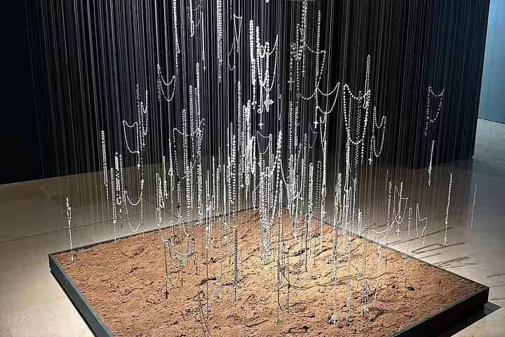 Intricate art installation with hanging beads over sand, featured in a Fátima day trip from Lisbon for small groups.