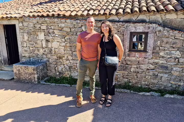 Couple enjoys a sunny day at a historic stone house in Fátima during a full-day private tour from Lisbon.