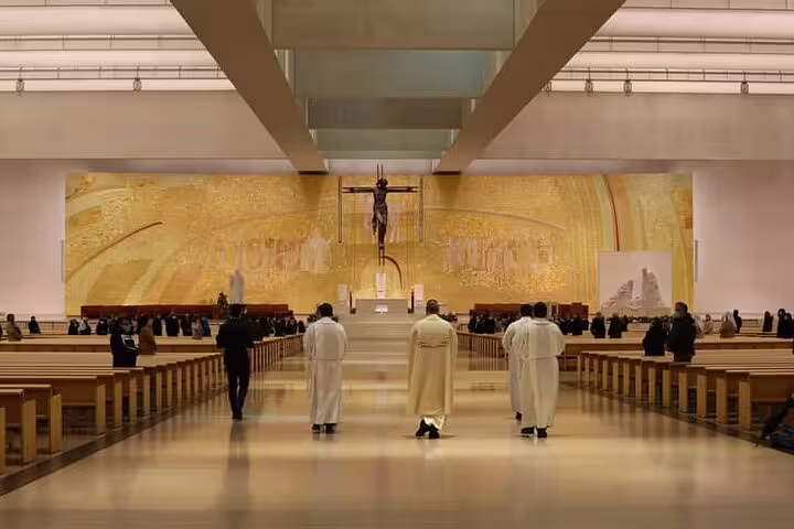 Interior of Fátima Sanctuary with clergy and visitors, showcasing the ornate altar, Lisbon small group day trip experience.