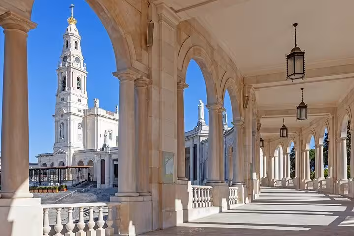 Architectural beauty of the Sanctuary of Fátima with elegant arches and a view of the basilica, perfect for cultural exploration.