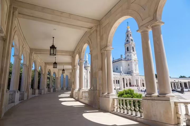Scenic view of the Sanctuary of Fátima's grand colonnade and basilica on a sunny day, featured in a private day trip from Lisbon.