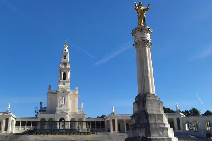 Stunning view of the Sanctuary of Fátima's basilica and monument under a clear blue sky, ideal for private Fatima and Coimbra tours.