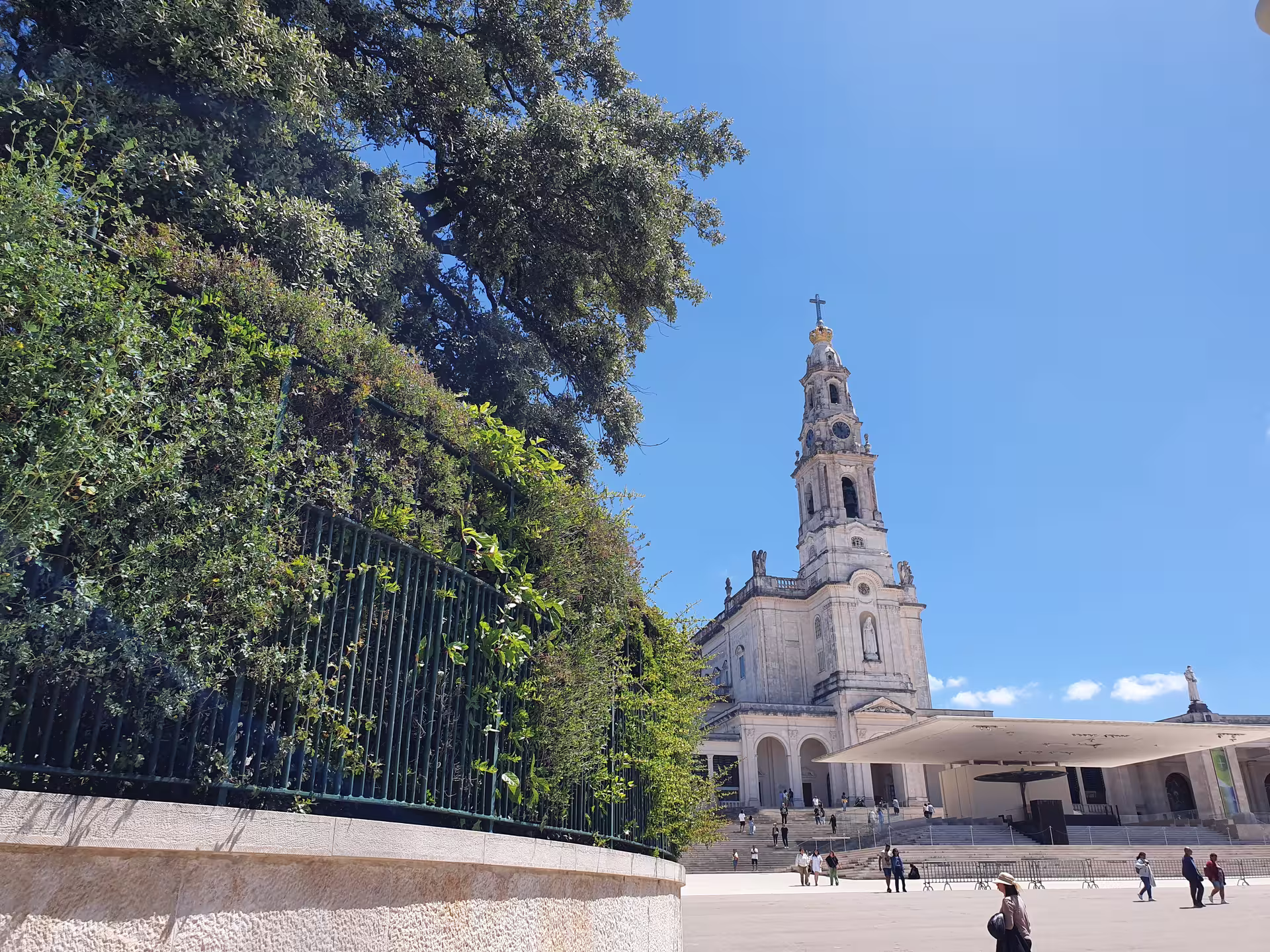 Scenic view of the Sanctuary of Fátima with its iconic basilica, lush greenery, and bright blue sky on a private tour from Lisbon.