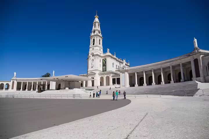 View of Sanctuary of Fátima with its grand basilica under a clear blue sky, a must-see on the Lisbon to Fátima tour.